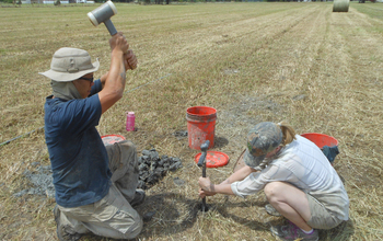 Two scientists collect riverbank samples.